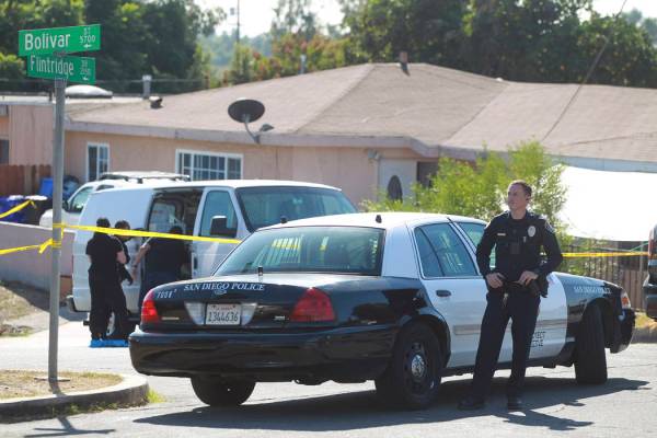 A San Diego Police officer stands in front of a home where two adults and three children died f ...