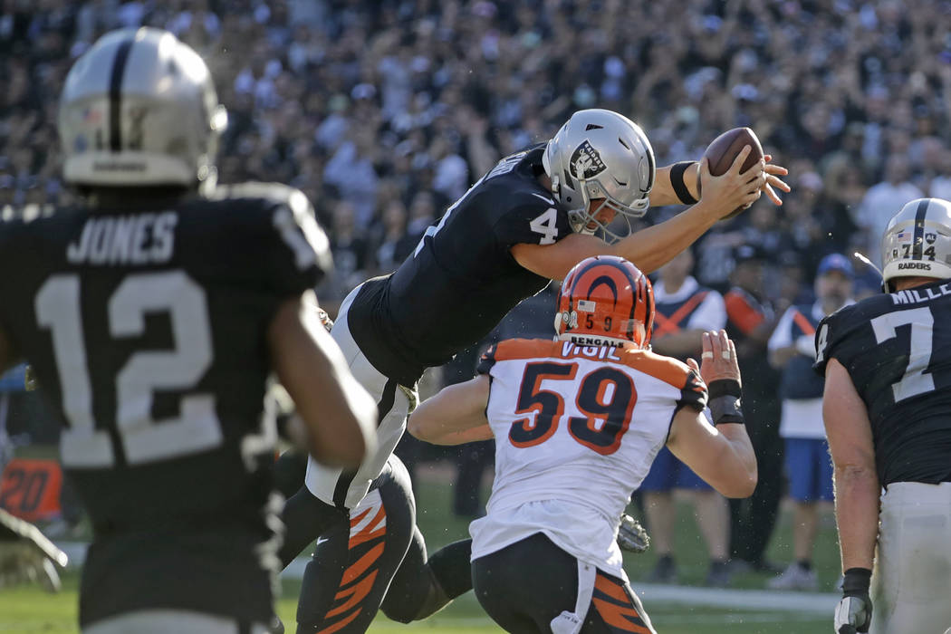 Oakland Raiders quarterback Derek Carr (4) leaps with the ball over the goal line to score a to ...