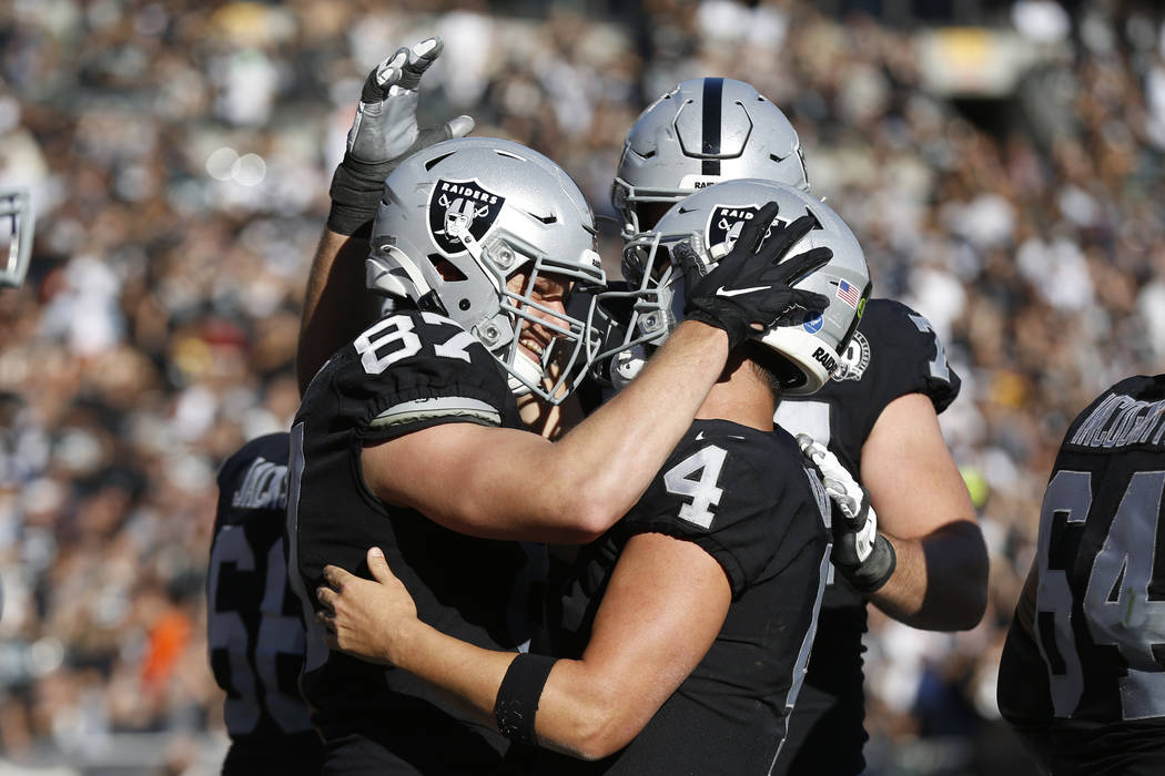 Oakland Raiders tight end Foster Moreau (87) is greeted by quarterback Derek Carr (4) after sco ...