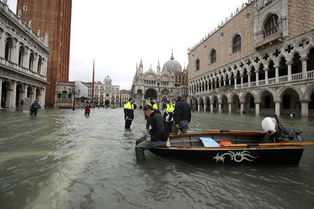 A man sits on a small boat in a flooded St.Mark square in Venice, Italy, Sunday, Nov. 17, 2019. ...