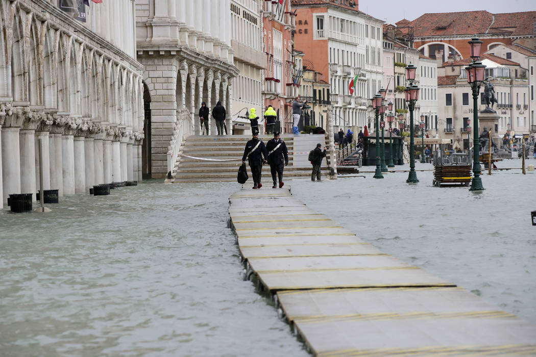 Two Carabinieri walk on a gangway in flooded Venice, Italy, Sunday, Nov. 17, 2019. Venetians ar ...