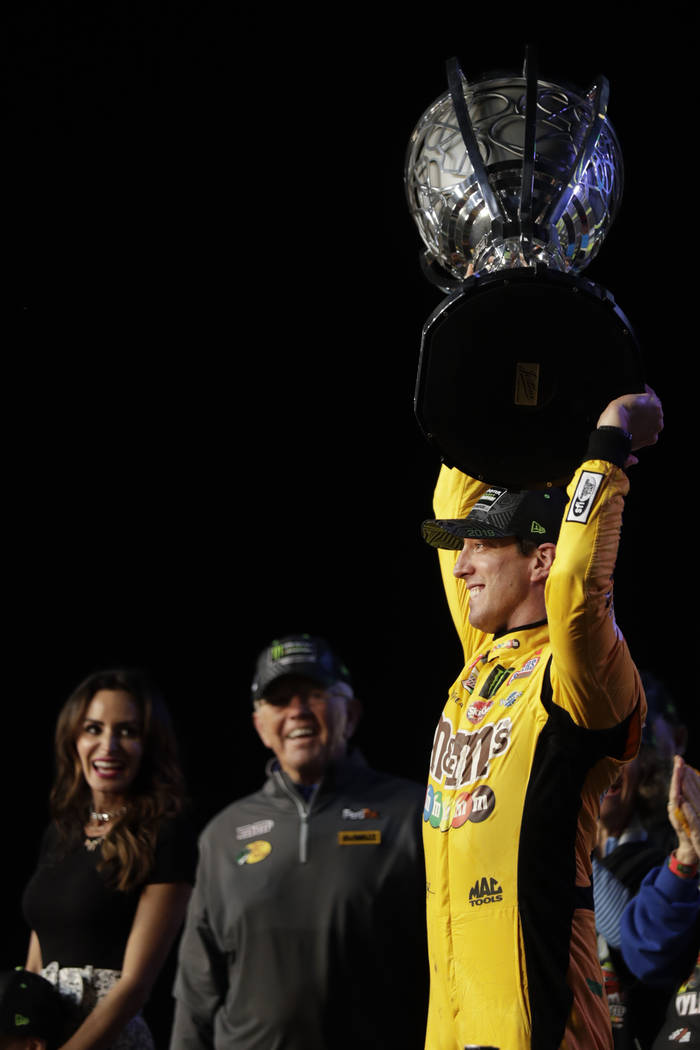 Kyle Busch, right, holds up his trophy in Victory Lane after winning a NASCAR Cup Series auto r ...
