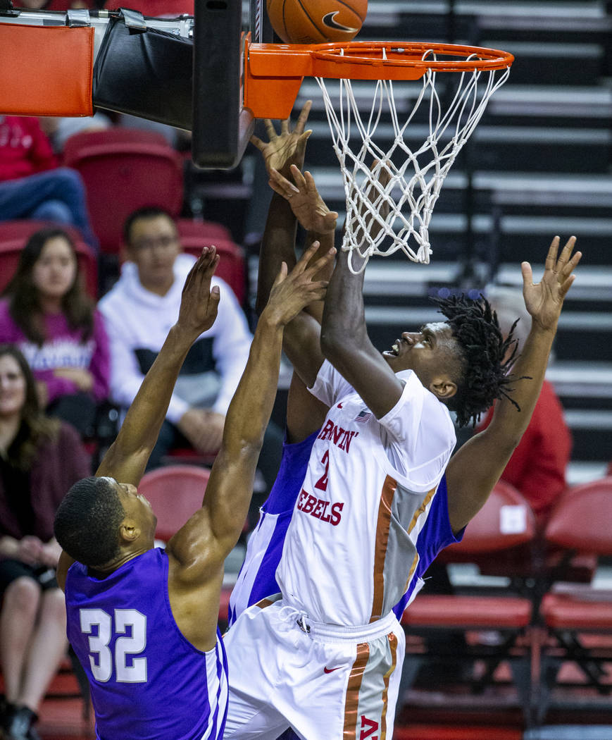 UNLV Rebels forward Donnie Tillman (2, center) gets off a shot over tight defense at the rim by ...