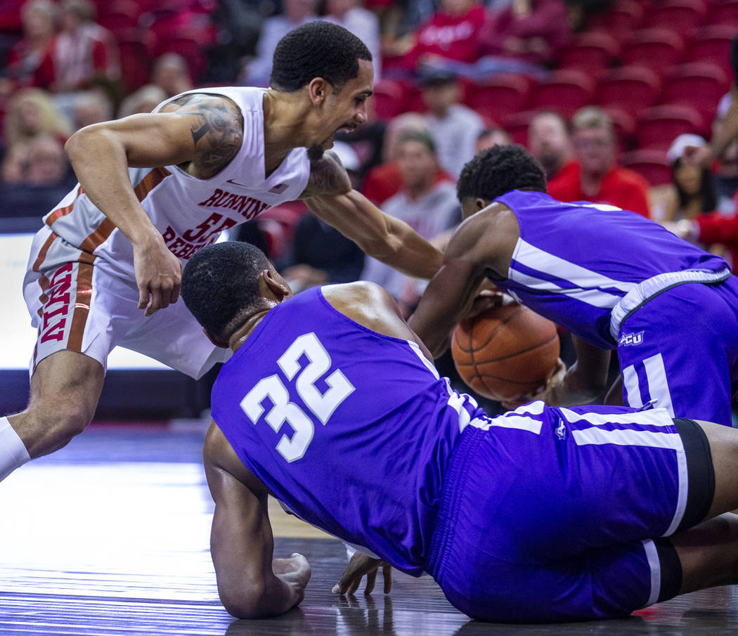 UNLV Rebels guard Elijah Mitrou-Long (55, left) gets a hand on a loose ball with a challenge fr ...