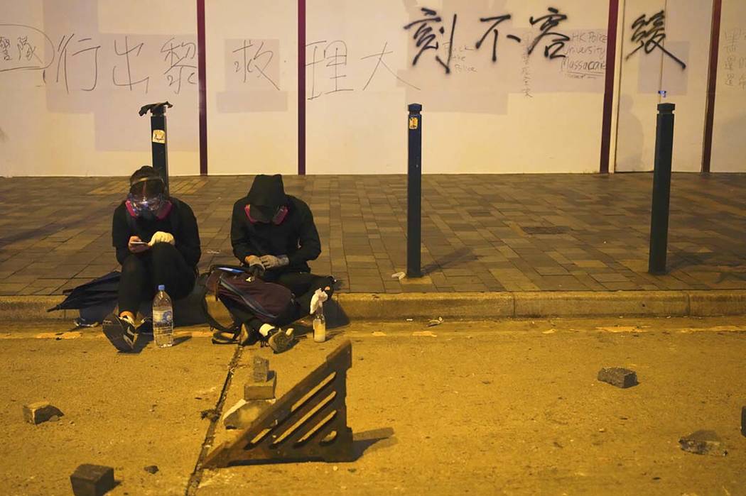 Protestors rest near a road barricaded with bricks in Hong Kong, early Tuesday, Nov. 19, 2019. ...