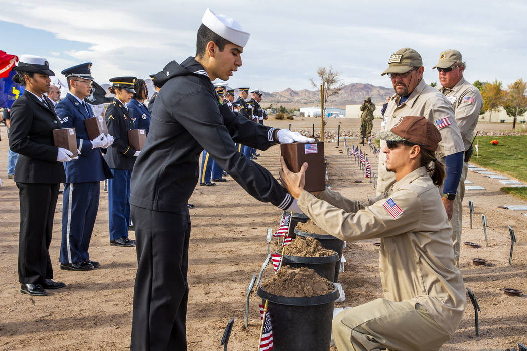 Seaman Alex Ramirez presents an urn for burial to Brandon Hall with the Southern Nevada Veteran ...