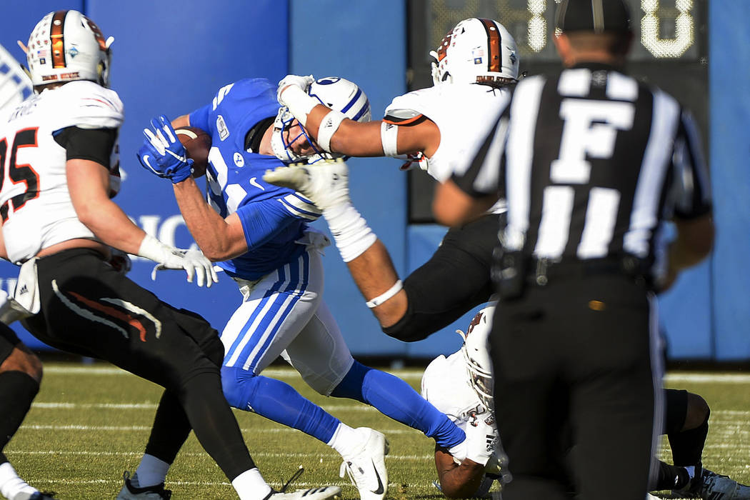 BYU wide receiver Talon Shumway (21) gets his head wrenched by Idaho State defensive back Manas ...