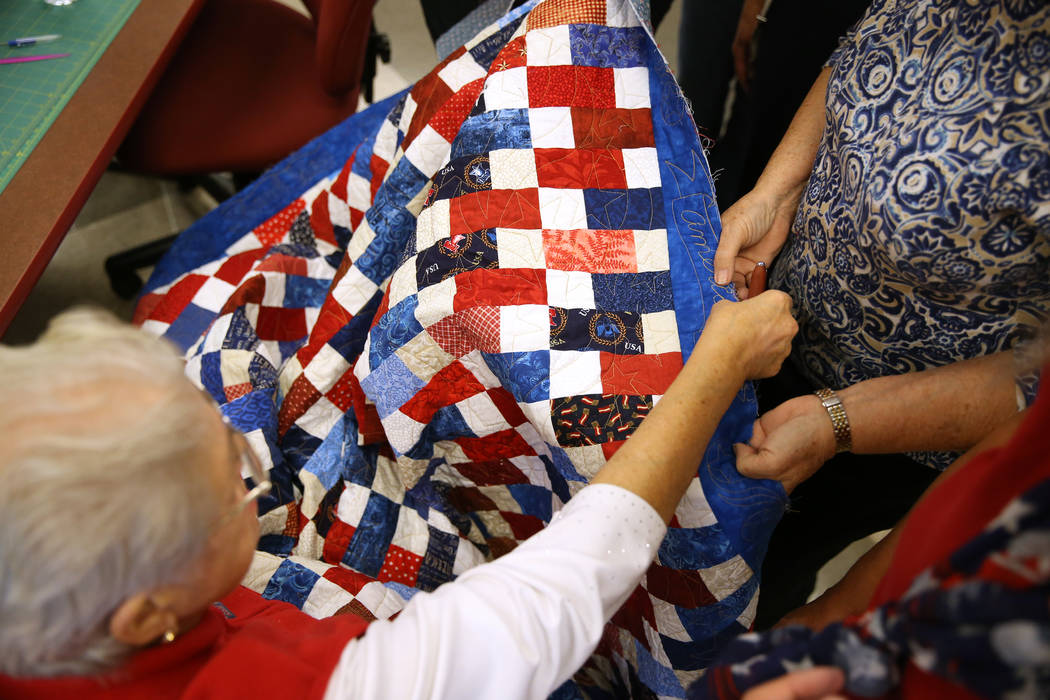 Members of Quilters for Veterans talk to resolve a problem with a quilt during a meet by the gr ...