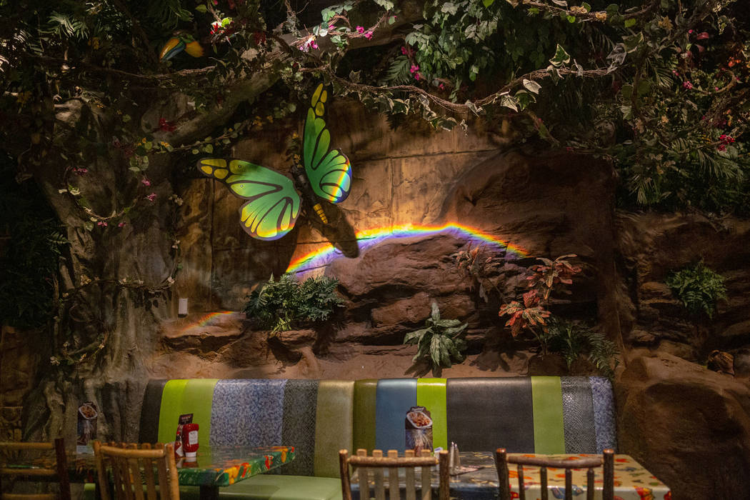 Dining tables covered by plants and mechanical animals in the Rainforest Cafe on the Las Vegas ...