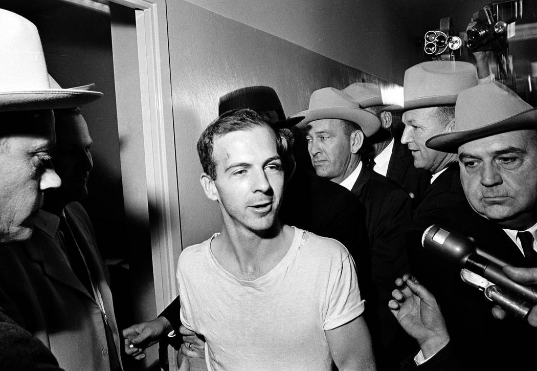 In this Nov. 23, 1963 file photo, surrounded by detectives, Lee Harvey Oswald talks to the pres ...