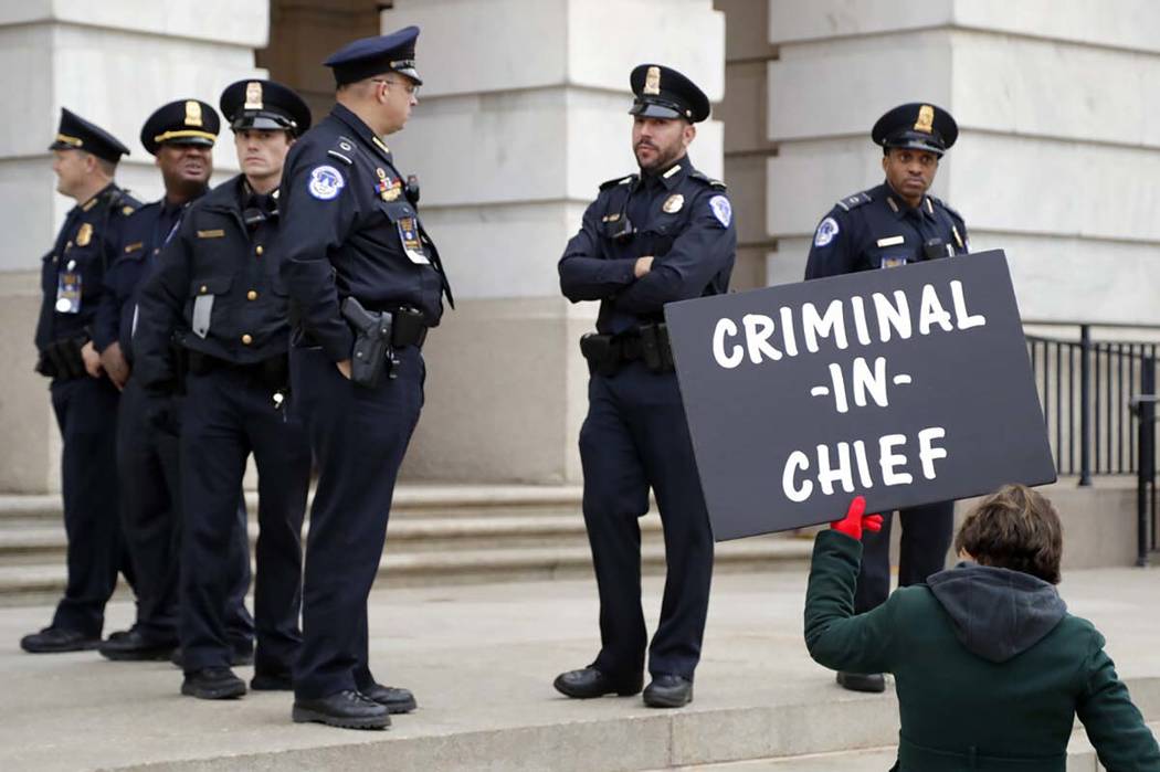 Capitol Police officers stand near a demonstrator holding a sign outside of Longworth House Off ...