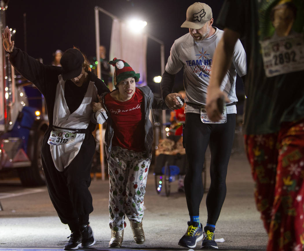 Blanca Tenhet, left, and Benjamin Bohman, right, help Taylor Capsuoto across the finish line as ...