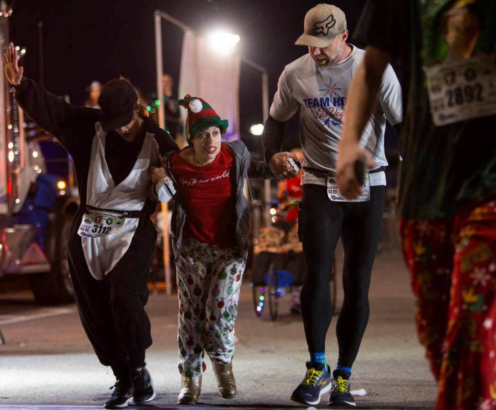 Blanca Tenhet, left, and Benjamin Bohman, right, help Taylor Capsuoto across the finish line as ...