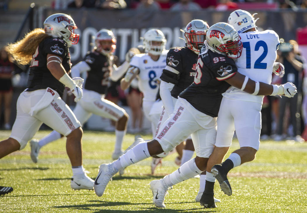 UNLV Rebels defensive lineman Jalen Graves (95, center) slams into San Jose State Spartans quar ...