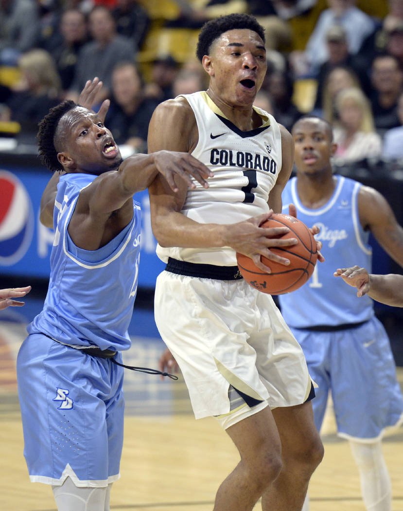 Colorado guard Tyler Bey, right, pulls in a rebound as San Diego center James Jean-Marie defend ...