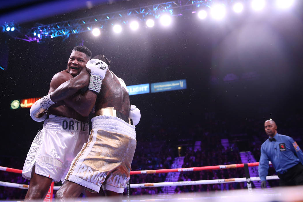 Luis Ortiz, left, smirks as he holds on to Deontay Wilder during the seventh round of the WBC h ...