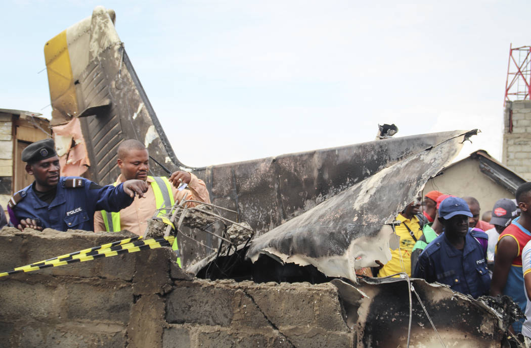 Rescuers and onlookers gather amidst the debris of an aircraft operated by private carrier Busy ...