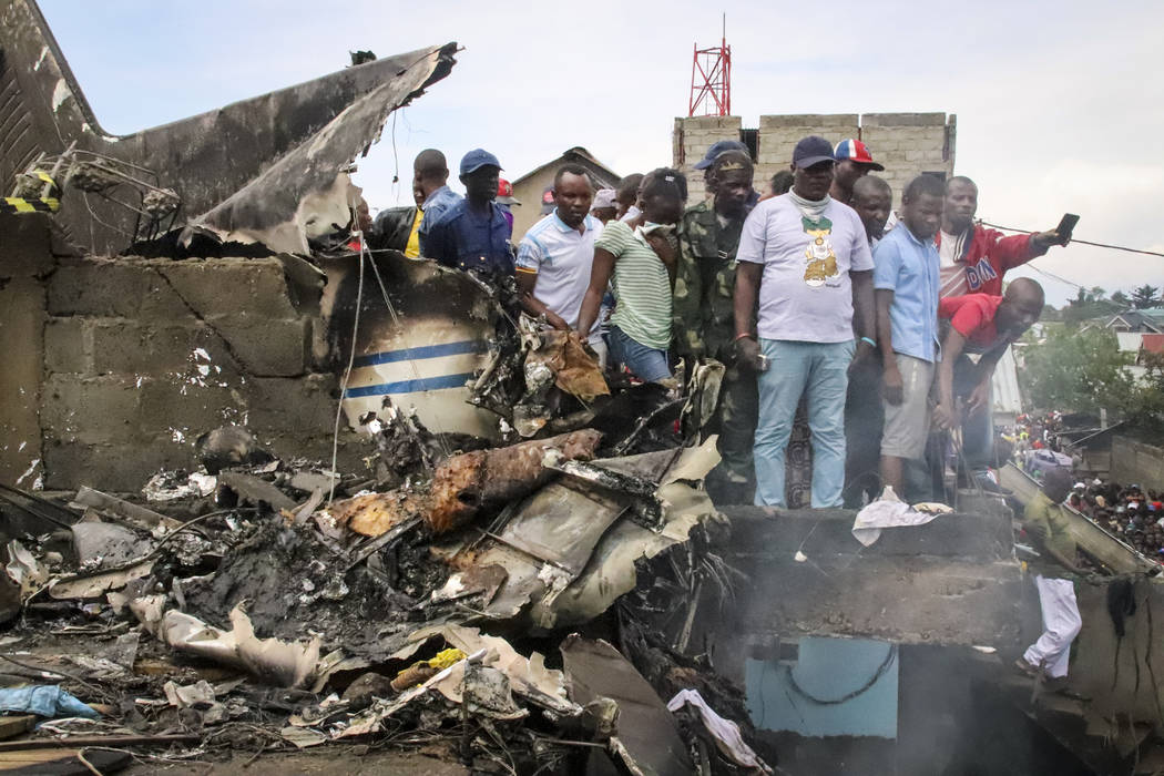 Rescuers and onlookers gather amidst the debris of an aircraft operated by private carrier Busy ...