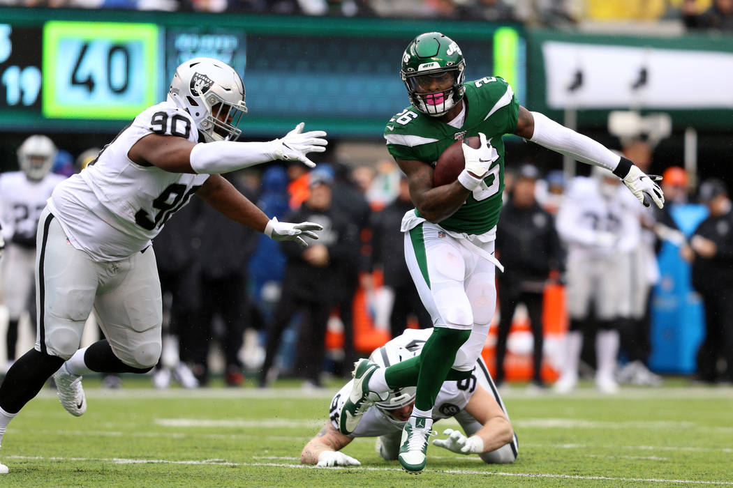 New York Jets running back Le'Veon Bell (26) sheds a tackle from Oakland Raiders defensive end ...