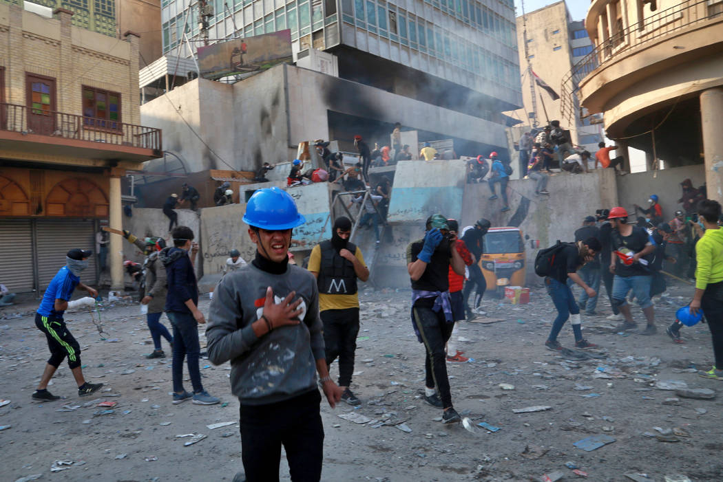 Protesters react to tear gas fired by riot police during clashes between security forces and an ...