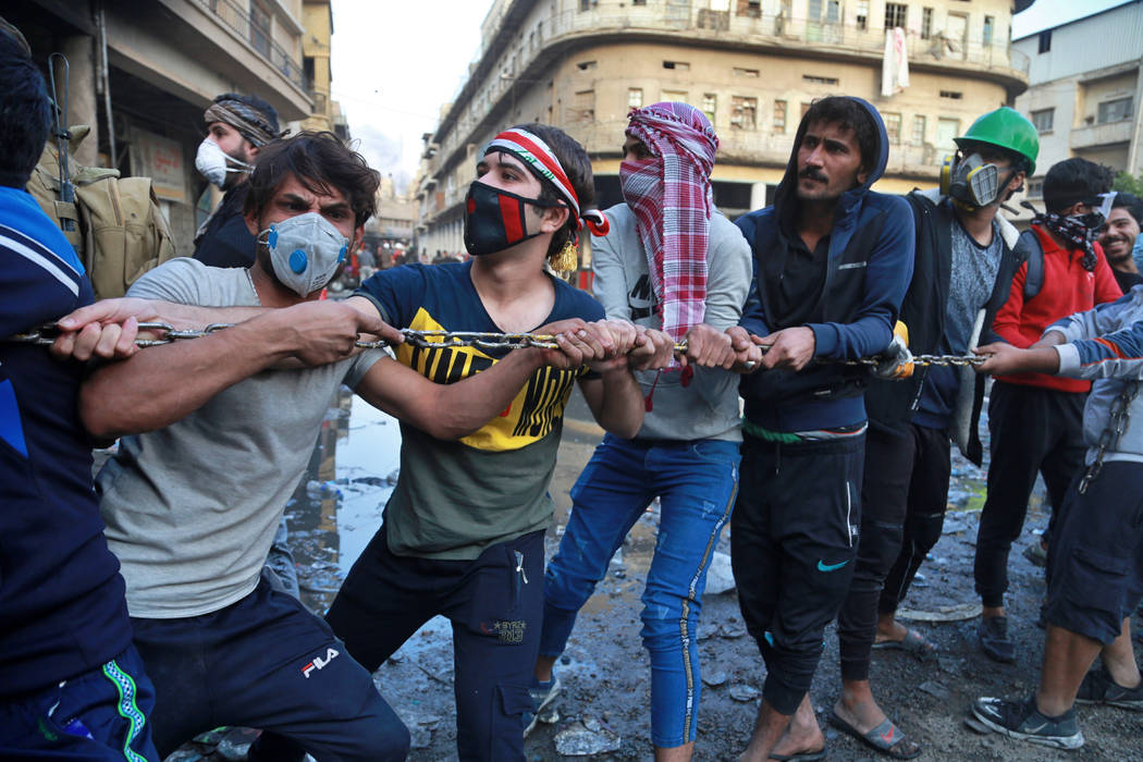 Demonstrators try to pull down concrete walls placed by Iraqi security forces to close in the h ...