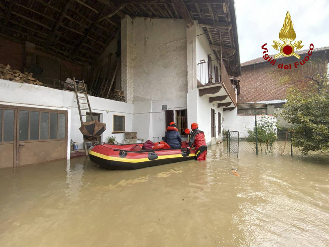 Firefighters on a dinghy evacuate people from house in Carde', near Cuneo, in the Piedmont regi ...