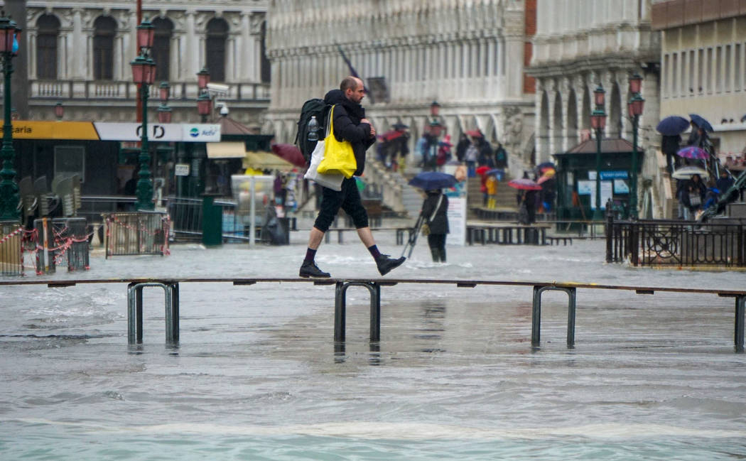 A man walks on a trestle bridge as high water floods Venice, northern Italy, Sunday, Nov. 24, 2 ...