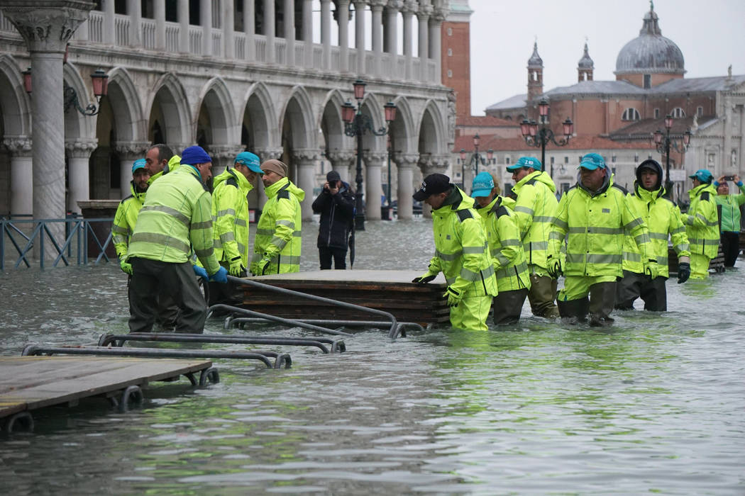 Workers install trestle bridge as high water floods Venice, northern Italy, Sunday, Nov. 24, 20 ...