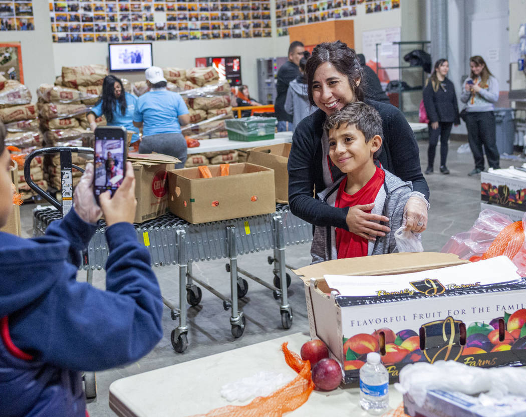 Volunteers with Vegas United Soccer Club Michelle Kannya, left, and Joah Kannya, 10, take a pho ...