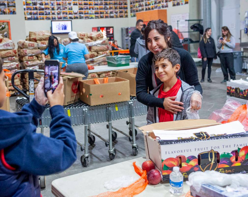 Volunteers with Vegas United Soccer Club Michelle Kannya, left, and Joah Kannya, 10, take a pho ...