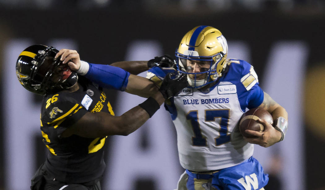 Winnipeg Blue Bombers quarterback Chris Streveler pushes away Hamilton Tiger-Cats' Cariel Brook ...