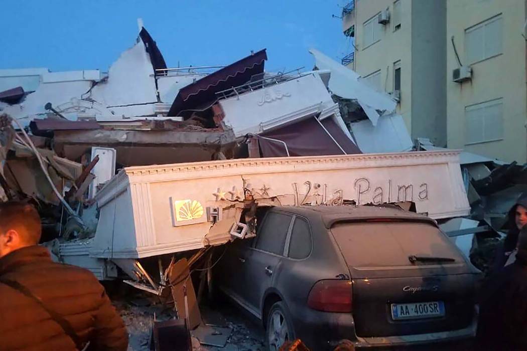 People stand next to a damaged hotel after an earthquake, in Durres, western Albania, Tuesday, ...