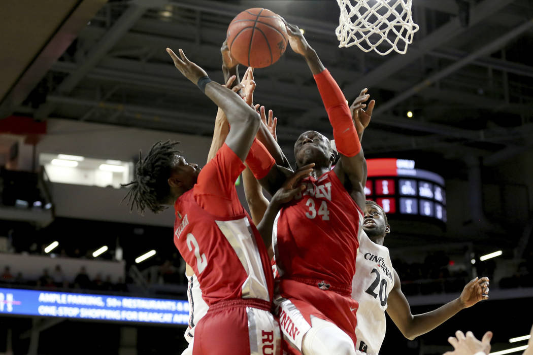 UNLV forward Cheikh Mbacke Diong (34) pulls down a rebound next to Cincinnati forward Mamoudou ...