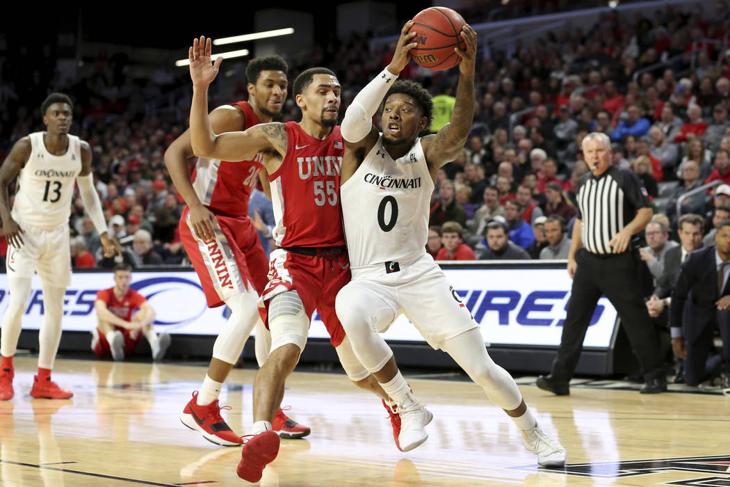 Cincinnati guard Chris McNeal (0) drives to the basket as UNLV guard Elijah Mitrou-Long (55) de ...