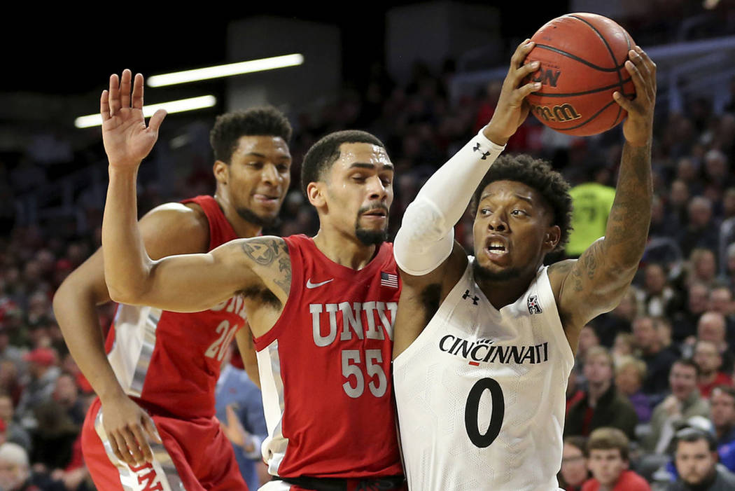 Cincinnati guard Chris McNeal (0) drives to the basket as UNLV guard Elijah Mitrou-Long (55) de ...