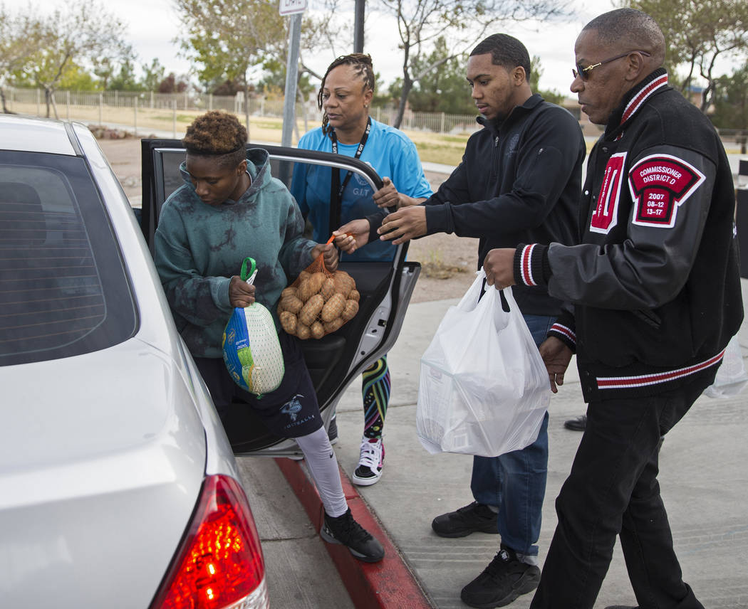 Sincere Basped, left, loads a car with turkey and potatoes with the help of Gene Stokes and Cla ...