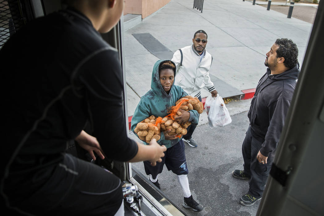 Sincere Basped, second from left, and Mark Smitty deliver Thanksgiving dinners to a bus during ...