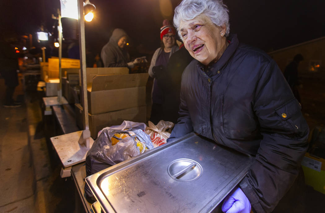 Volunteer Christine Ruland helps to serve some hot dinner to those in need gathered for the Giv ...