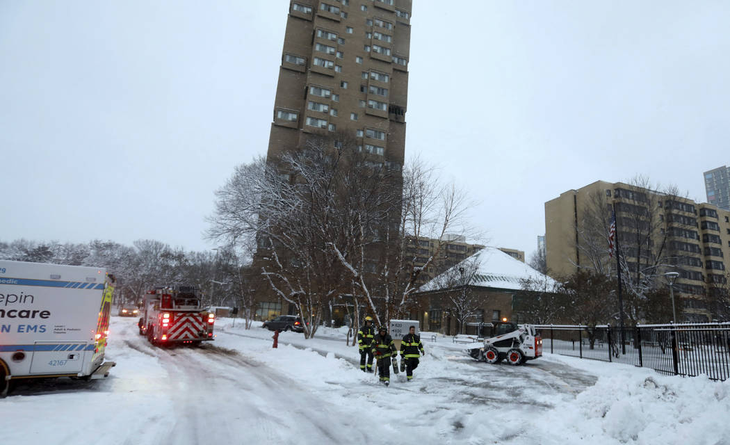 Minneapolis firefighters leave after a deadly fire at a high-rise apartment building, center in ...