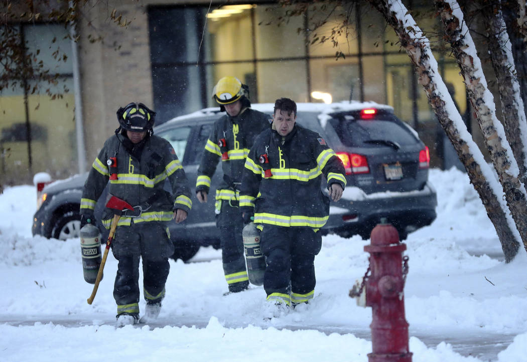 Minneapolis firefighters leave high-rise apartment building after a deadly fire Wednesday, Nov. ...