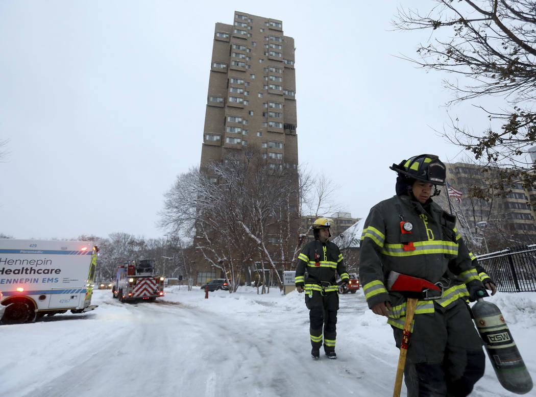 Minneapolis firefighters leave after a deadly fire at a high-rise apartment building, in backgr ...