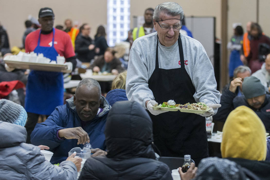 Volunteer Alan Kotwica, top/right, serves a tray of food during the Las Vegas Rescue Mission's ...