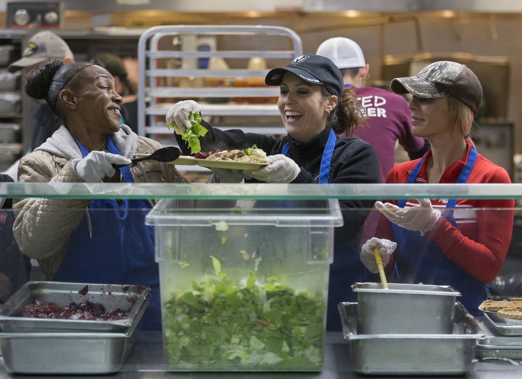 Volunteers Yolanda Grimes, left, Beth Louton and Jamie Almasi prepare trays of food during the ...