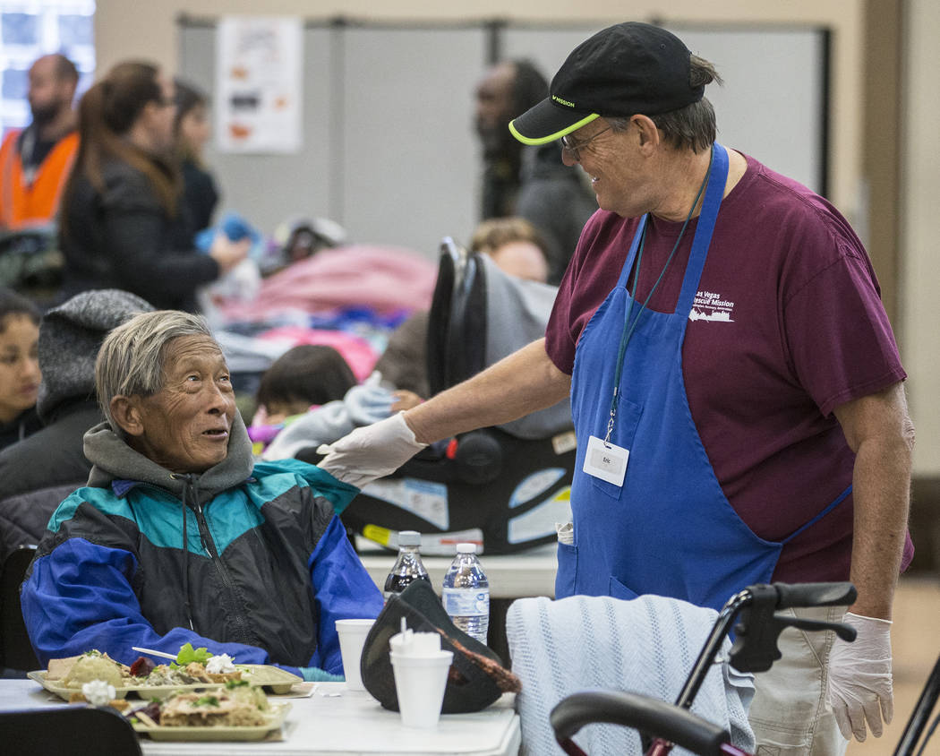 Volunteer Eric Marsh, right, talks with Yeng Huang while Huang eats at the Las Vegas Rescue Mis ...