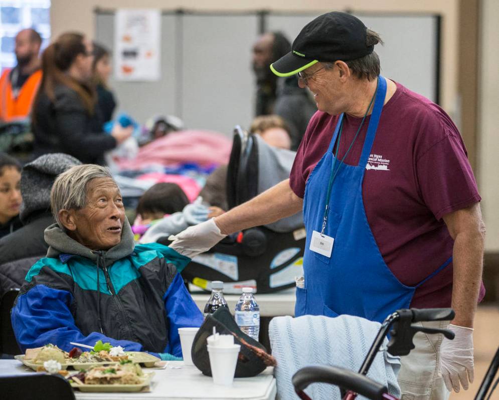 Volunteer Eric Marsh, right, talks with Yeng Huang while Huang eats at the Las Vegas Rescue Mis ...