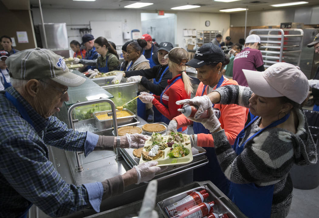 Edna Sanders, top/right, Sara Cottingham and Joe Kubacki prepare trays of food during the Las V ...