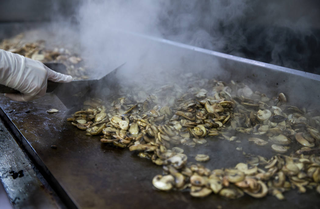 Steam rises from a grill full of mushrooms being prepared as Catholic Charities of Southern Nev ...