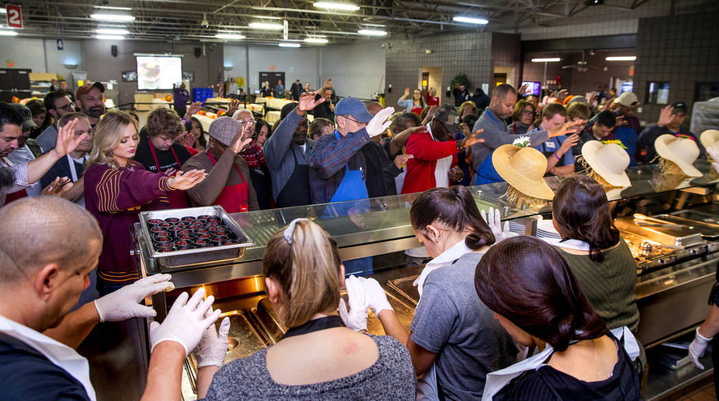 Volunteers come together for a group prayer over the food as Catholic Charities of Southern Nev ...