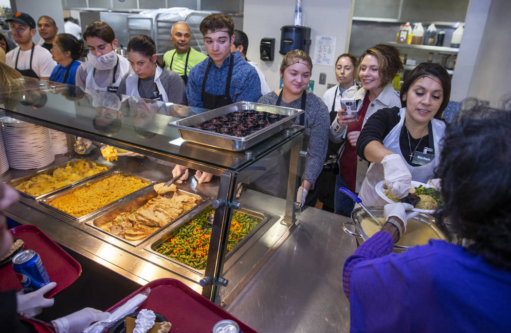 Volunteers including Selva Montoya, right, begin to prepare plates of food as Catholic Charitie ...