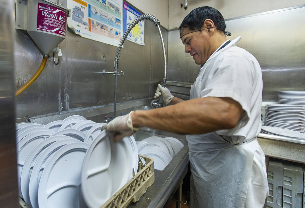 Jun Lata works to help clean the dishes as Catholic Charities of Southern Nevada serves its 54t ...